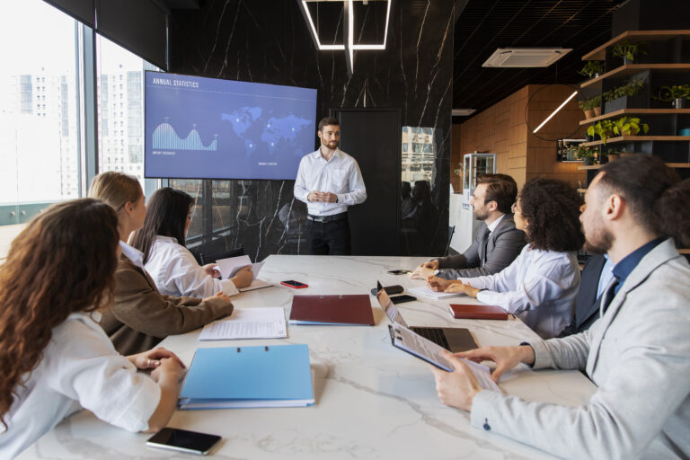 Business professionals in a meeting discussing strategy around a conference table, showcasing collaboration and modern leadership culture